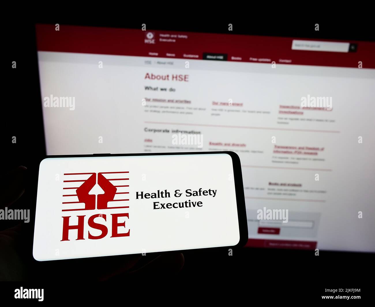 Person, die das Smartphone mit dem Logo der britischen Agentur Health and Safety Executive (HSE) auf dem Bildschirm vor der Website hält. Konzentrieren Sie sich auf die Telefonanzeige. Stockfoto