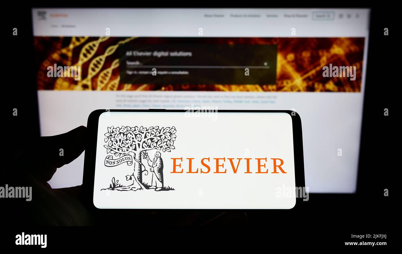 Person, die das Smartphone mit dem Logo des akademischen Verlags Elsevier auf dem Bildschirm vor der Website hält. Konzentrieren Sie sich auf die Telefonanzeige. Stockfoto