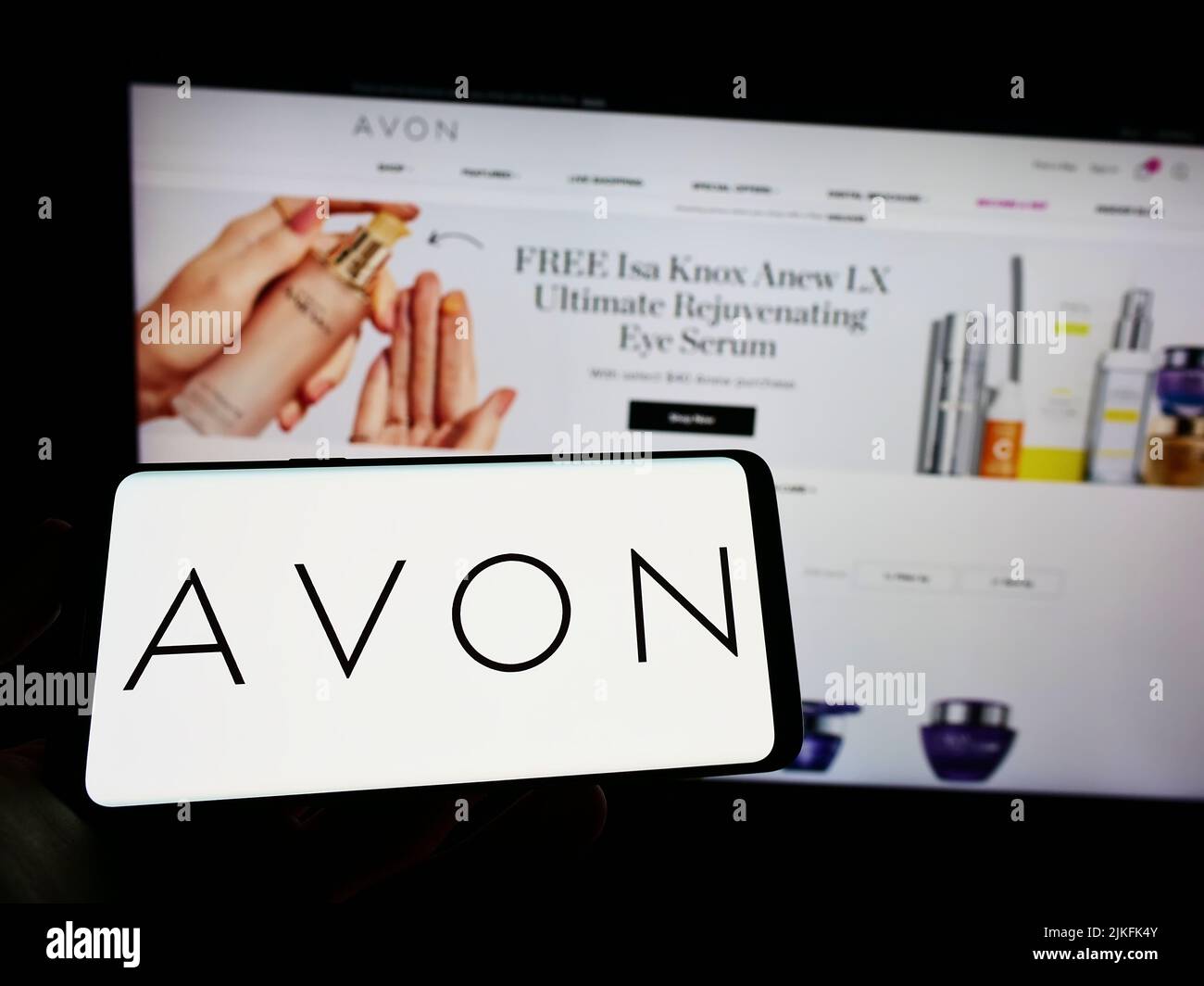 Person, die Mobiltelefon mit dem Logo des Kosmetikunternehmens Avon Products Inc. Auf dem Bildschirm vor der Business-Webseite hält. Konzentrieren Sie sich auf die Telefonanzeige. Stockfoto