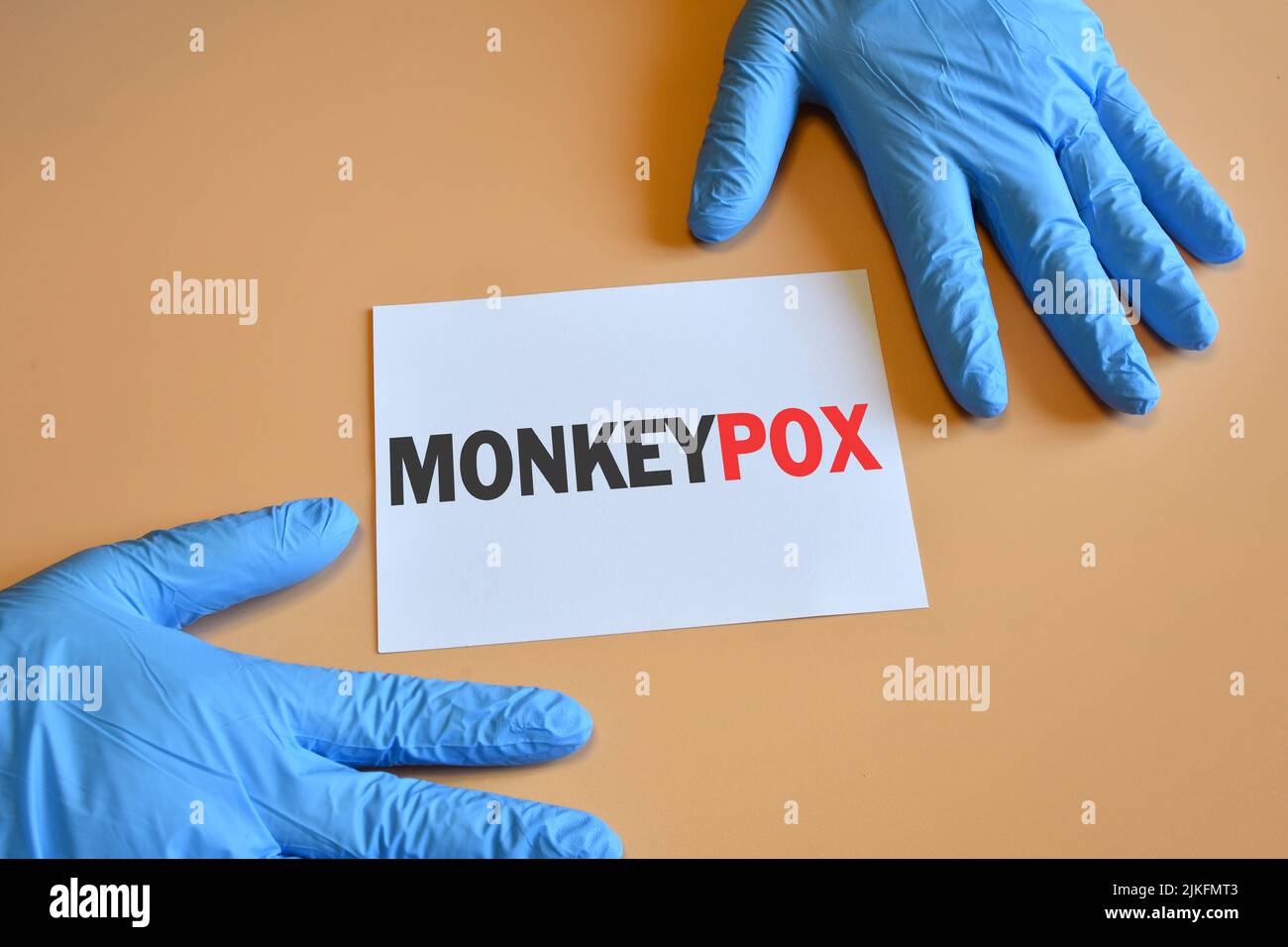 Monkeypox-Virus. Die Hände des Arztes in blauen Handschuhen halten ein weißes Papier mit der Aufschrift „Monkeypox Virus“. Medizinisches und Monkeypox-Virus Pandemi Stockfoto