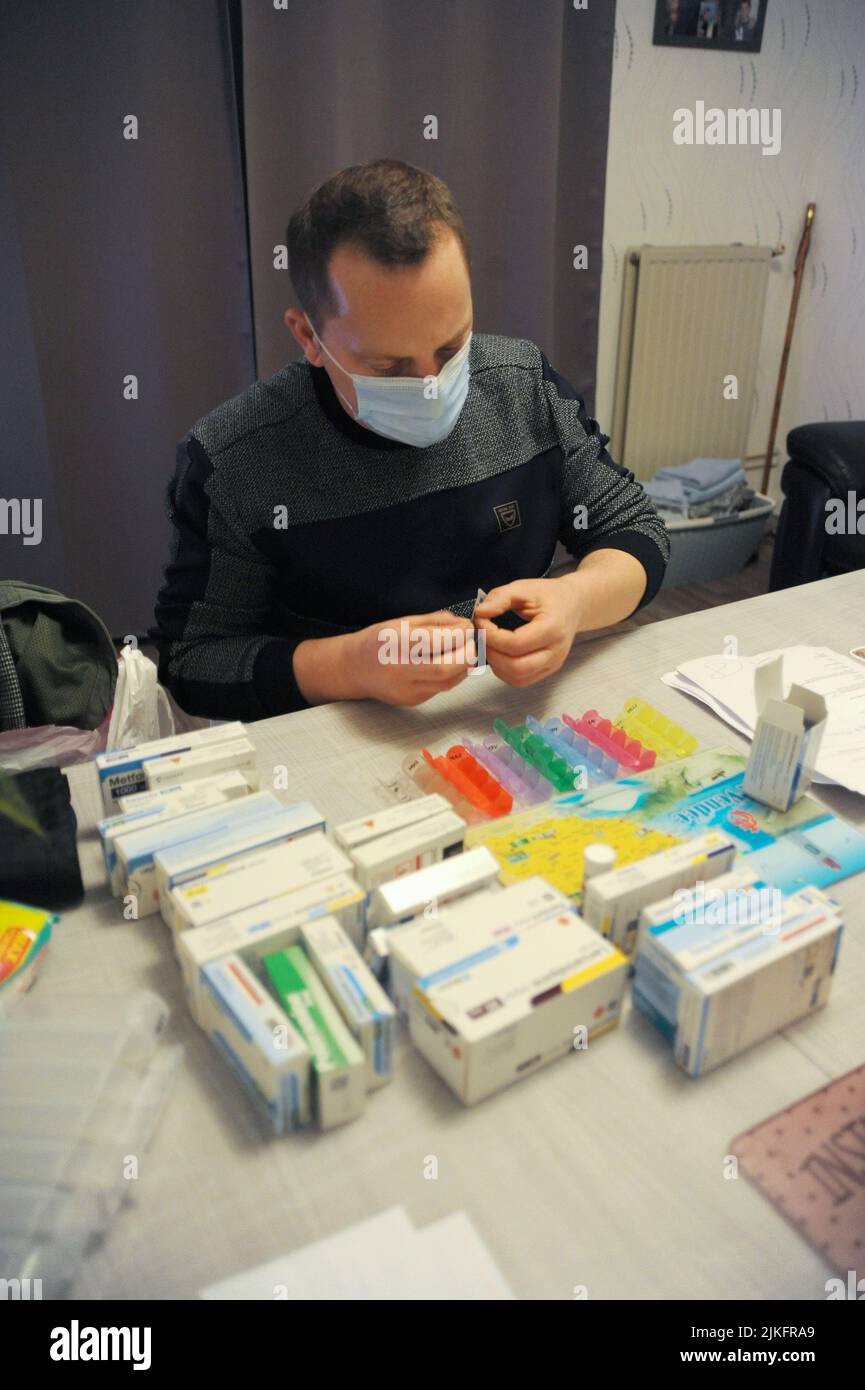 Eine private Krankenschwester bereitet bei einem Patienten zu Hause eine Pillenbox vor. Stockfoto