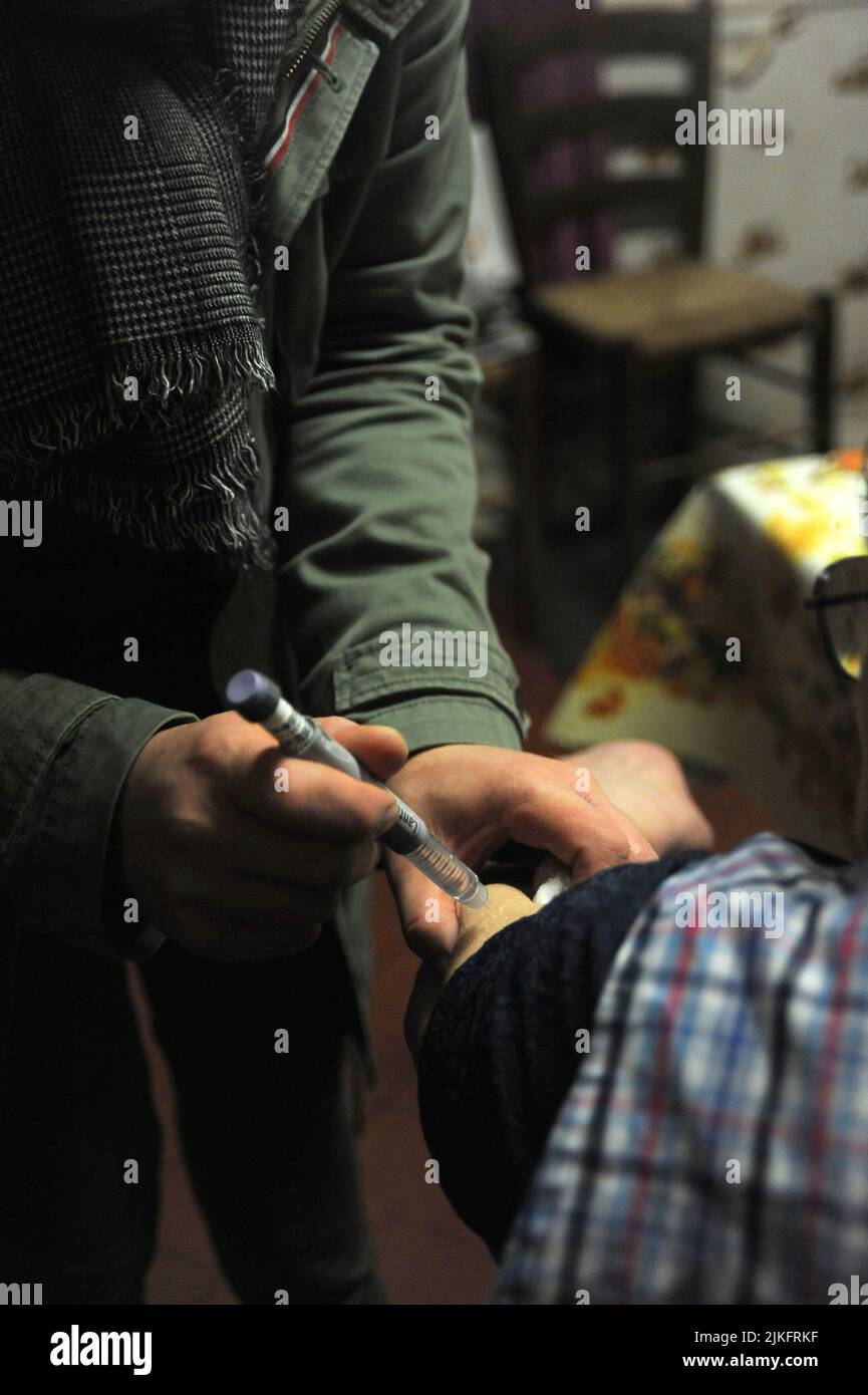 Private Krankenschwester im Haus eines 80-jährigen Patienten für die Montage von Kompressionsstrümpfen und einer Insulininspritze. Stockfoto