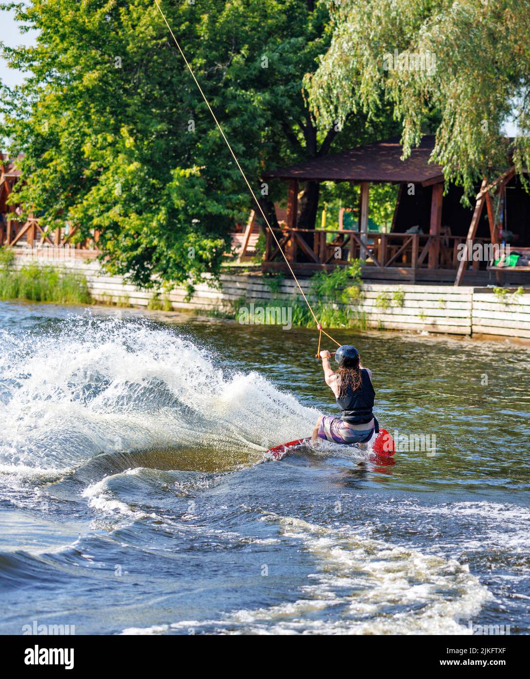 Wassersport, macht der Wakeboarder eine scharfe Wendung auf dem Wasser und wirft eine Welle und viel Spray. Stockfoto