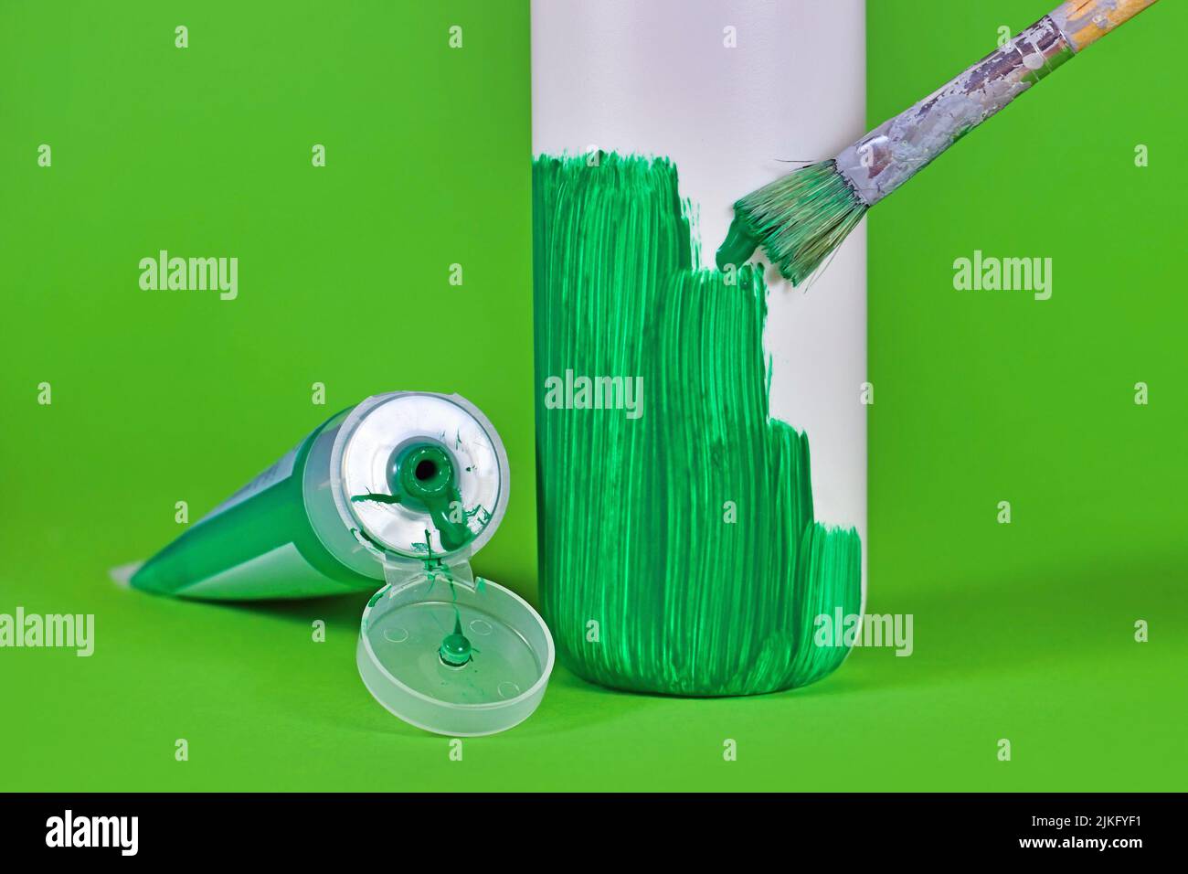 Konzept für Greenwashing mit weißer Kunststoffflasche, die grün lackiert wird Stockfoto