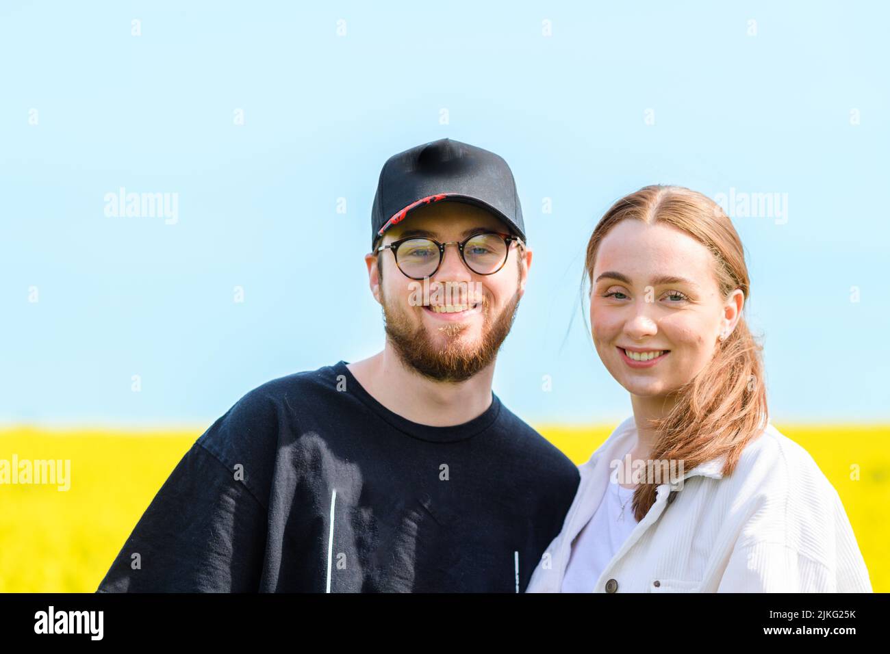 Ein glückliches junges kaukasisches Paar, das in einem gelben Feld posiert Stockfoto