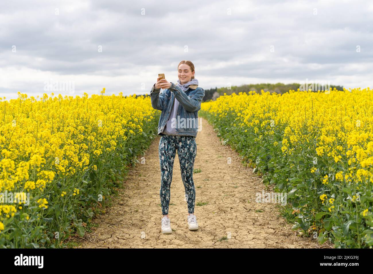 Ein junges kaukasisches Mädchen, das Fotos vom weißen Senffeld gemacht hat Stockfoto