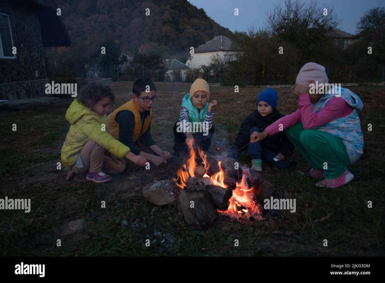 Eine Gruppe von Kindern im Lager aalen am Feuer. Schüler spielen und heizen im Herbst im Freien Stockfoto