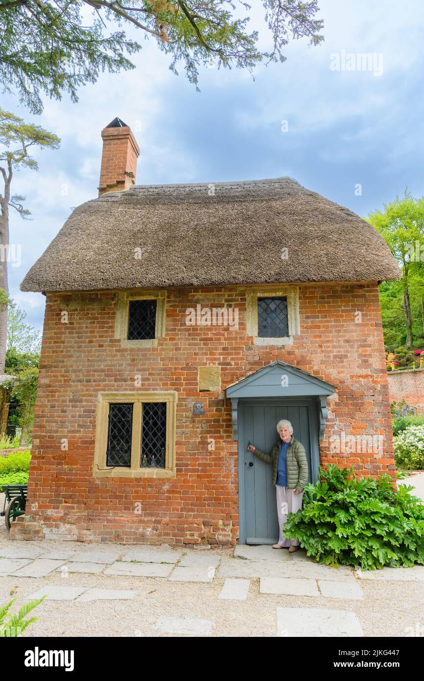 Eine vertikale Aufnahme einer alten, stilvollen kaukasischen Frau, die vor einem Haus posiert Stockfoto