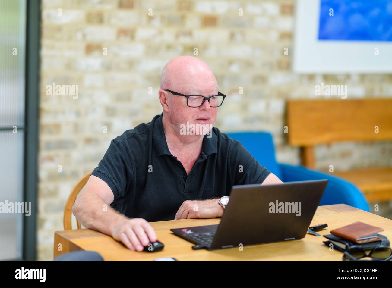 Eine Nahaufnahme eines kahlköpfigen kaukasischen Geschäftsmannes in einer Brille, an der gearbeitet wird, ist ein Laptop Stockfoto