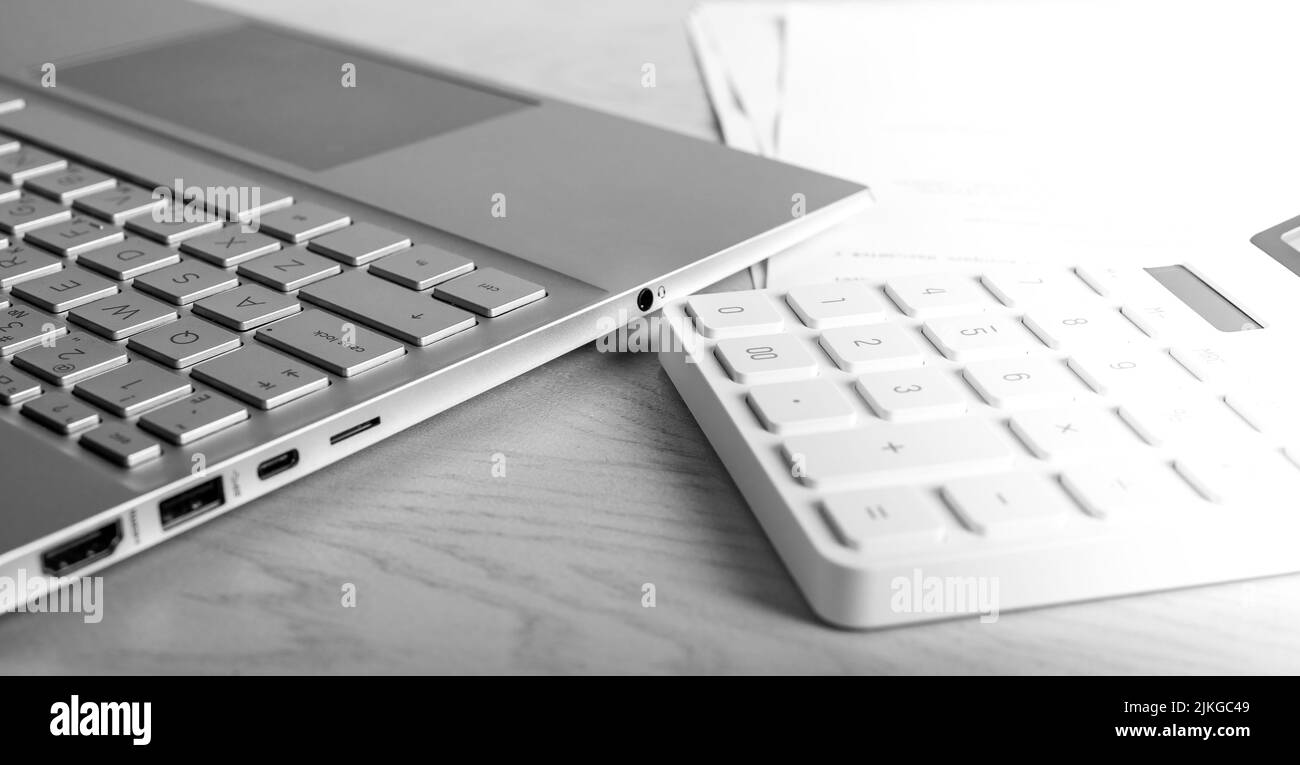 Laptop und Rechner am Tisch. Buchhalter, Arbeitsplatz. Statistische Daten, Erstellung eines analytischen Berichts. Hochwertige Fotos Stockfoto