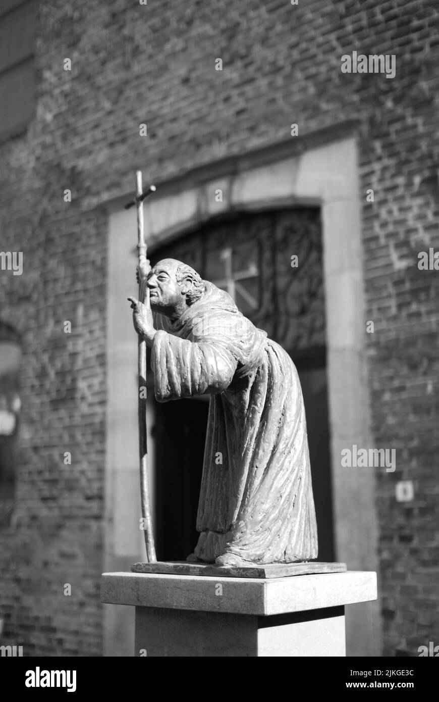 Eine Bronzeskulptur eines stillen Mönchs mit einem Kreuz in der Hand in Venlo, Niederlande Stockfoto