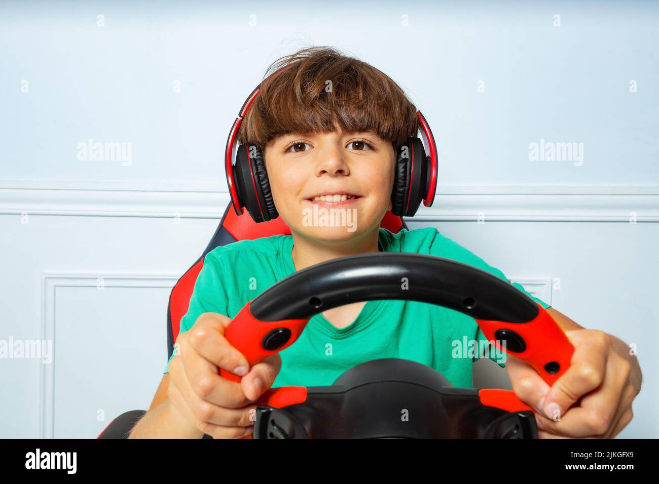 Happy Boy in Kopfhörer mit Lenkrad spielen Rennspiel Stockfoto