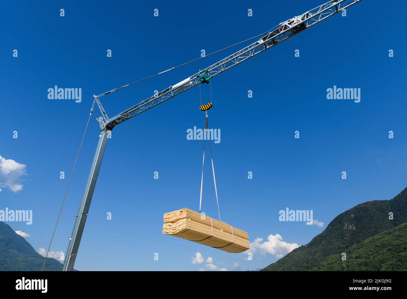 Baukran mit hängender Holzplanke auf blauem Himmel Stockfoto