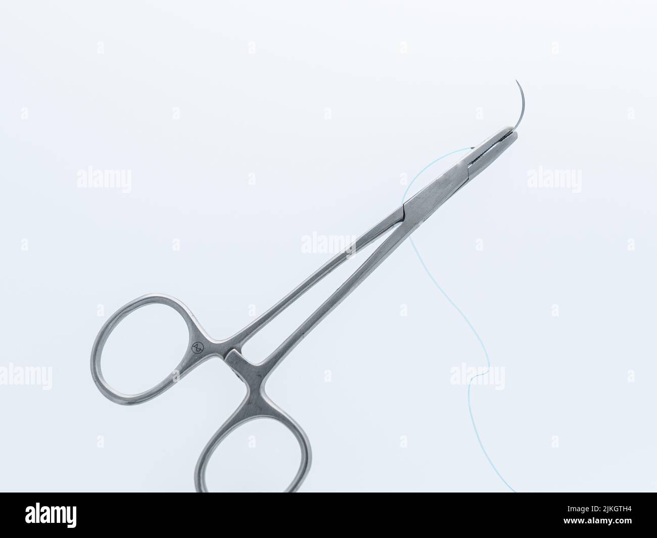 Eine chirurgische Nadel und ein Faden auf einer Nahtschere isoliert auf weißem Hintergrund Stockfoto