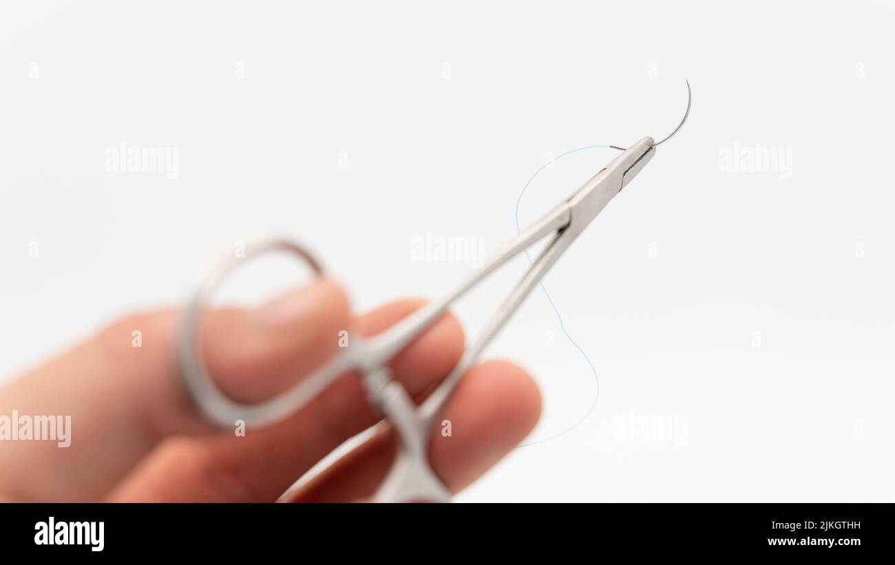 Eine chirurgische Nadel und ein Faden auf einer Nahtschere isoliert auf einem weißen Hintergrund Stockfoto
