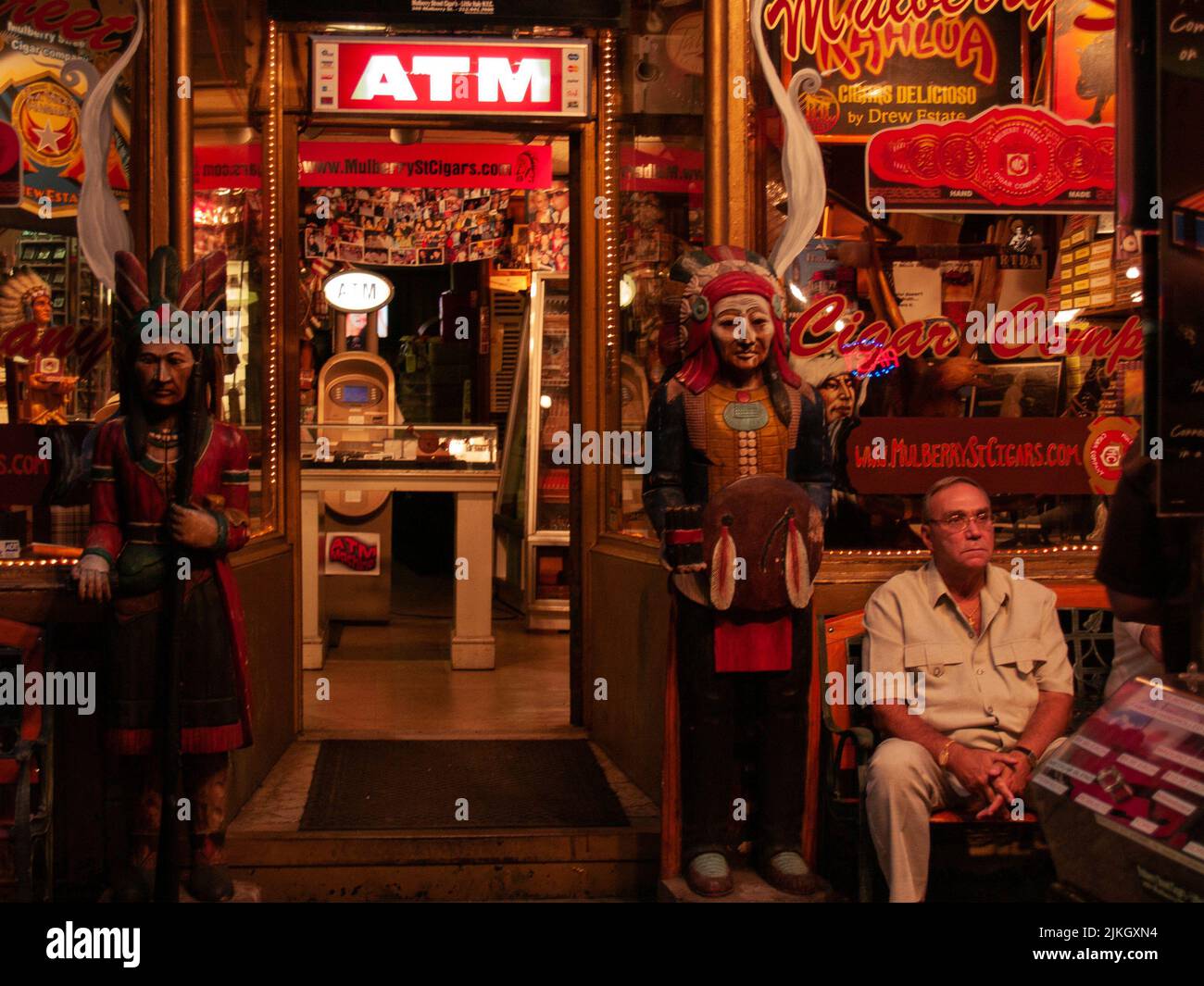 Ein erwachsener Mann, der vor einem Zigarrenladen in Little Italy, NYC, sitzt Stockfoto