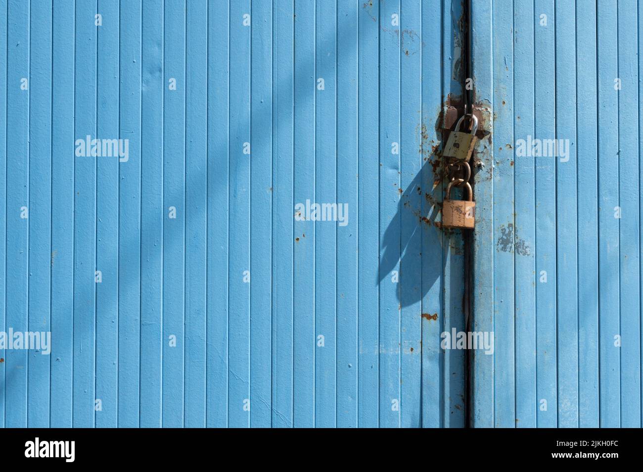 Ein blaues Metalltor mit zwei Vorhängeschlössern Stockfoto