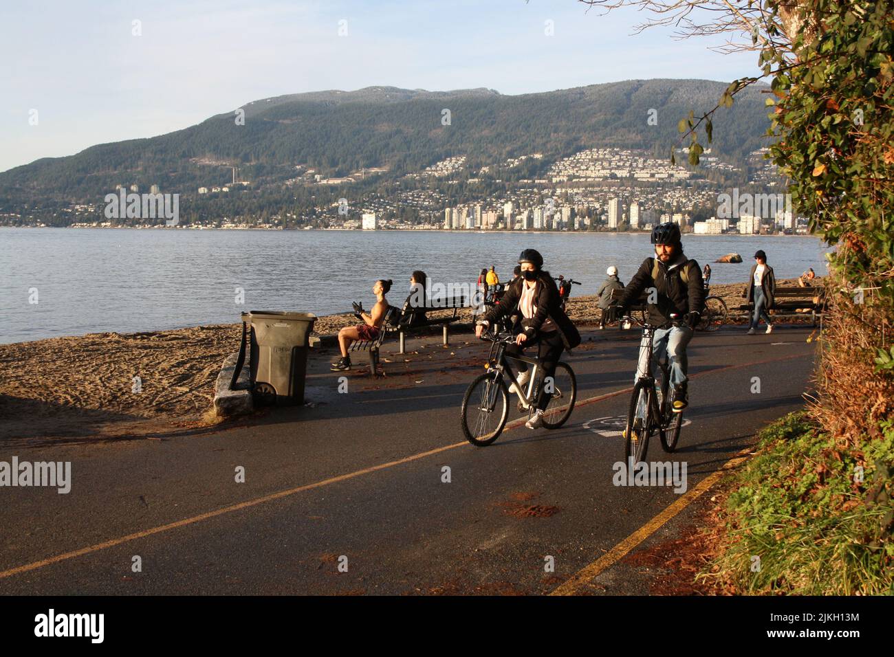 Ein Paar, das mit dem Fahrrad an Third Beach, Vancouver, British Columbia, Kanada vorbeifährt Stockfoto