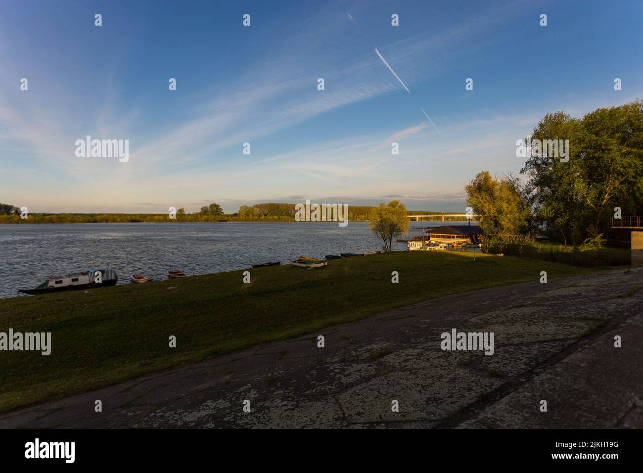 Eine malerische Aussicht auf grünen Rasen an einem Ufer eines Sees in goldener Stunde Stockfoto