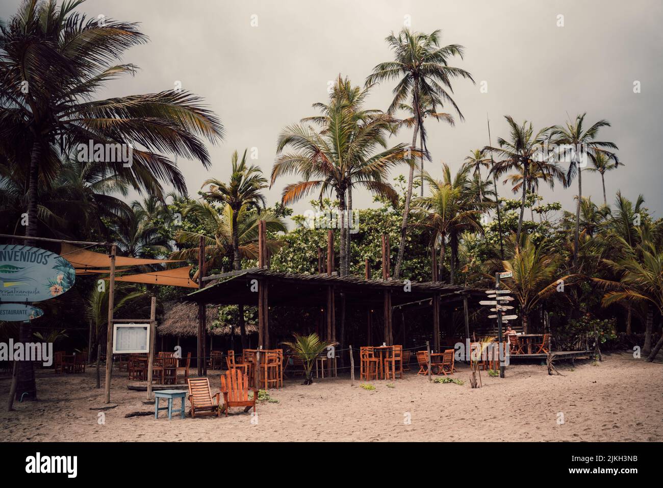 Eine malerische Aussicht auf ein leeres Café an einem Sandstrand gegen Palmen an einem bewölkten Tag Stockfoto