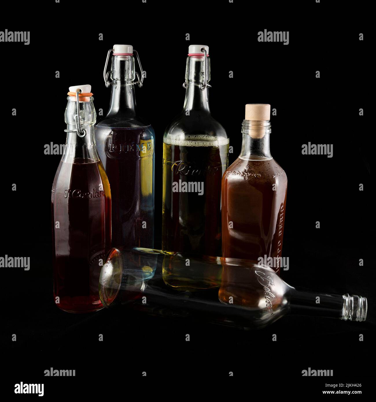 Eine vertikale Nahaufnahme von Flaschen, die zum Recycling bereit sind und mit Wasser und Lebensmittelfarben auf schwarzem Hintergrund gefüllt sind Stockfoto