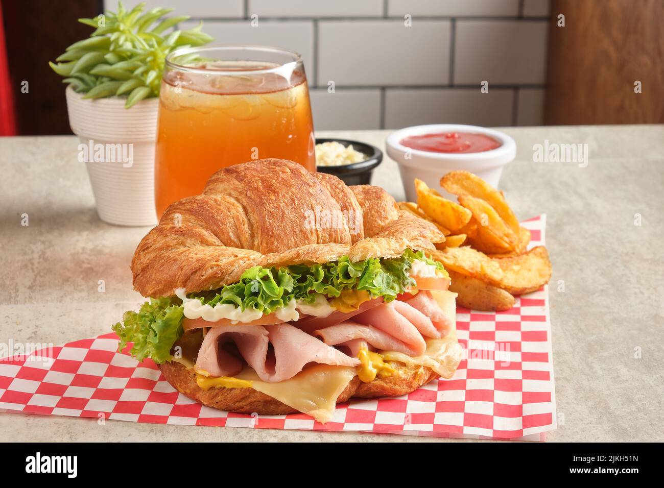 Ein köstliches Schinken- und Käsecroissant mit Sauce, Pommes Frites und Saft Stockfoto