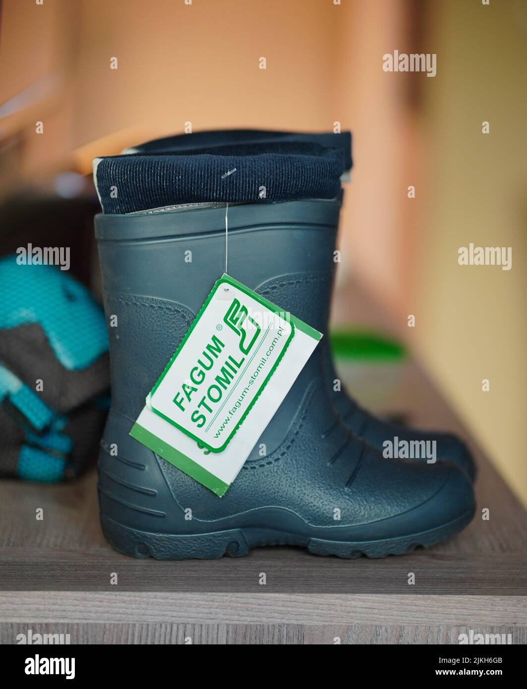 Eine Nahaufnahme von einem Paar Kinder-Regenstiefel auf einem grauen Holzregal mit verschwommenem Hintergrund Stockfoto