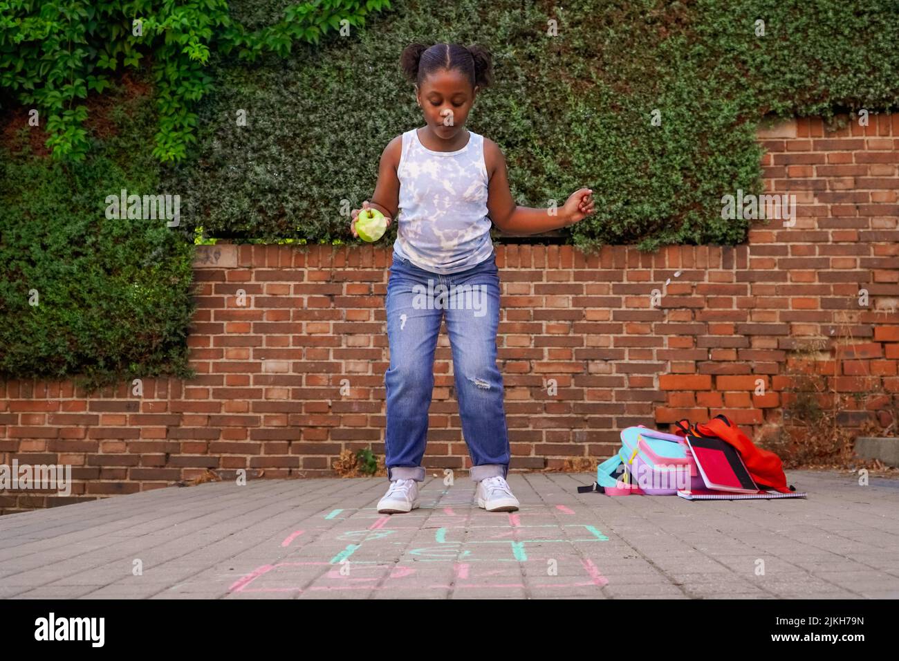 afro lateinamerikanische Mädchen hoppscotch auf Schulhof. Zurück zur Schule Konzept. Multiethnische Kindergruppe Stockfoto