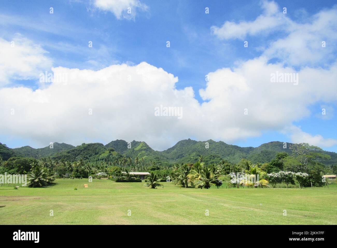 Ein Blick auf die grünen tropischen Berge von Rarotonga mit Regenwäldern und einem Feld davor Stockfoto
