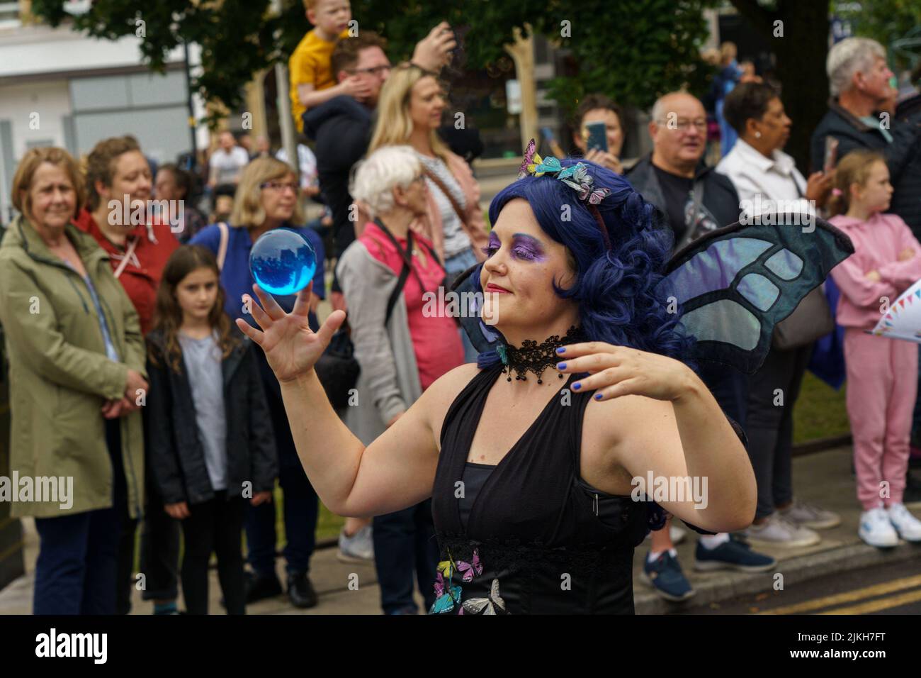 Leute, die die Harrogate Carnival Parade beobachten und ein Entertainer jongliert mit einer blauen Kristallkugel, Harrogate, North Yorkshire, Großbritannien Stockfoto