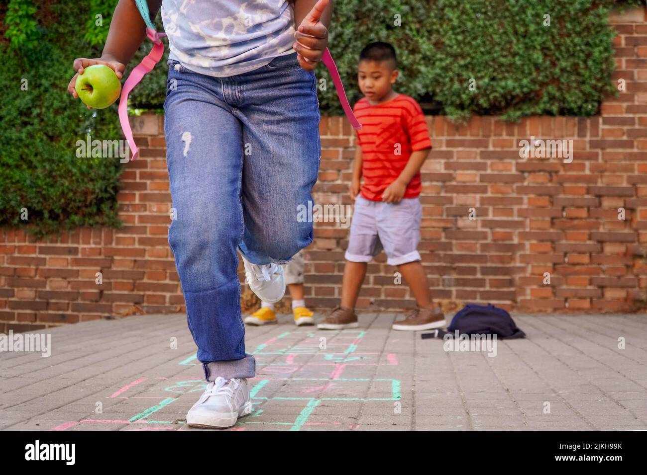 Multiethnische Kinder spielen hopscotch auf dem Schulhof. Zurück zum Schulkonzept. Multiethnische Kindergruppe Stockfoto