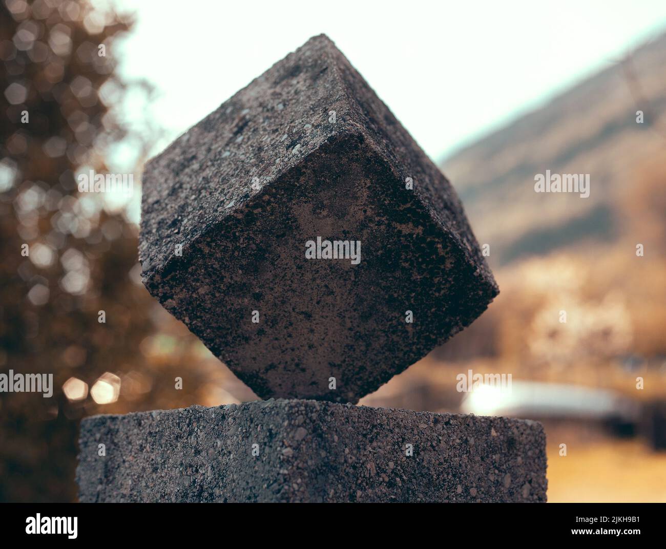 Eine Aufnahme eines Steinwürfels mit flachem Fokus auf horizontaler Oberfläche und unscharfem Hintergrund Stockfoto