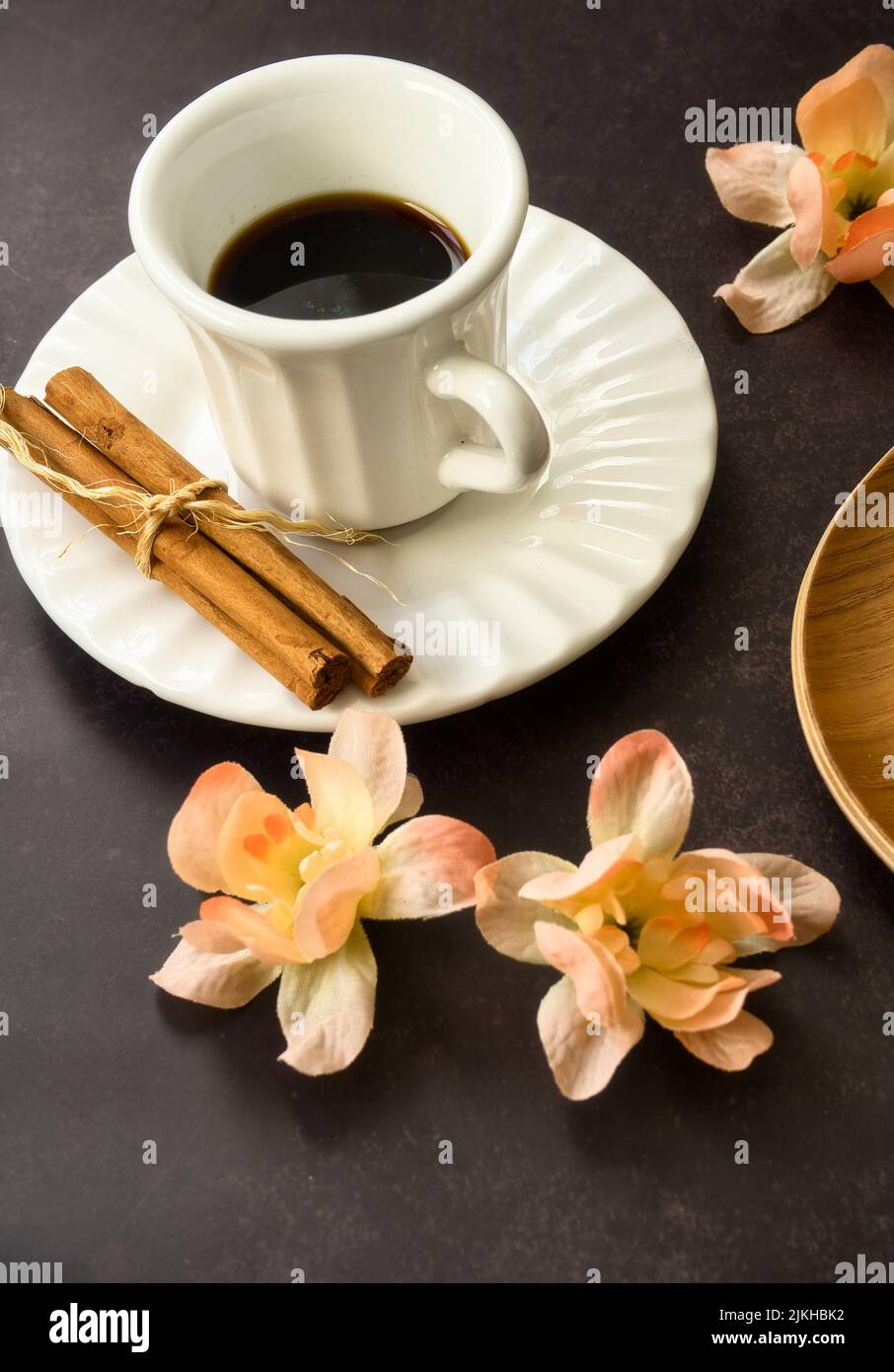 Tasse Kaffee mit Gebäck, dekoriert mit Frühlingsblumen auf dunklem Hintergrund. Stockfoto