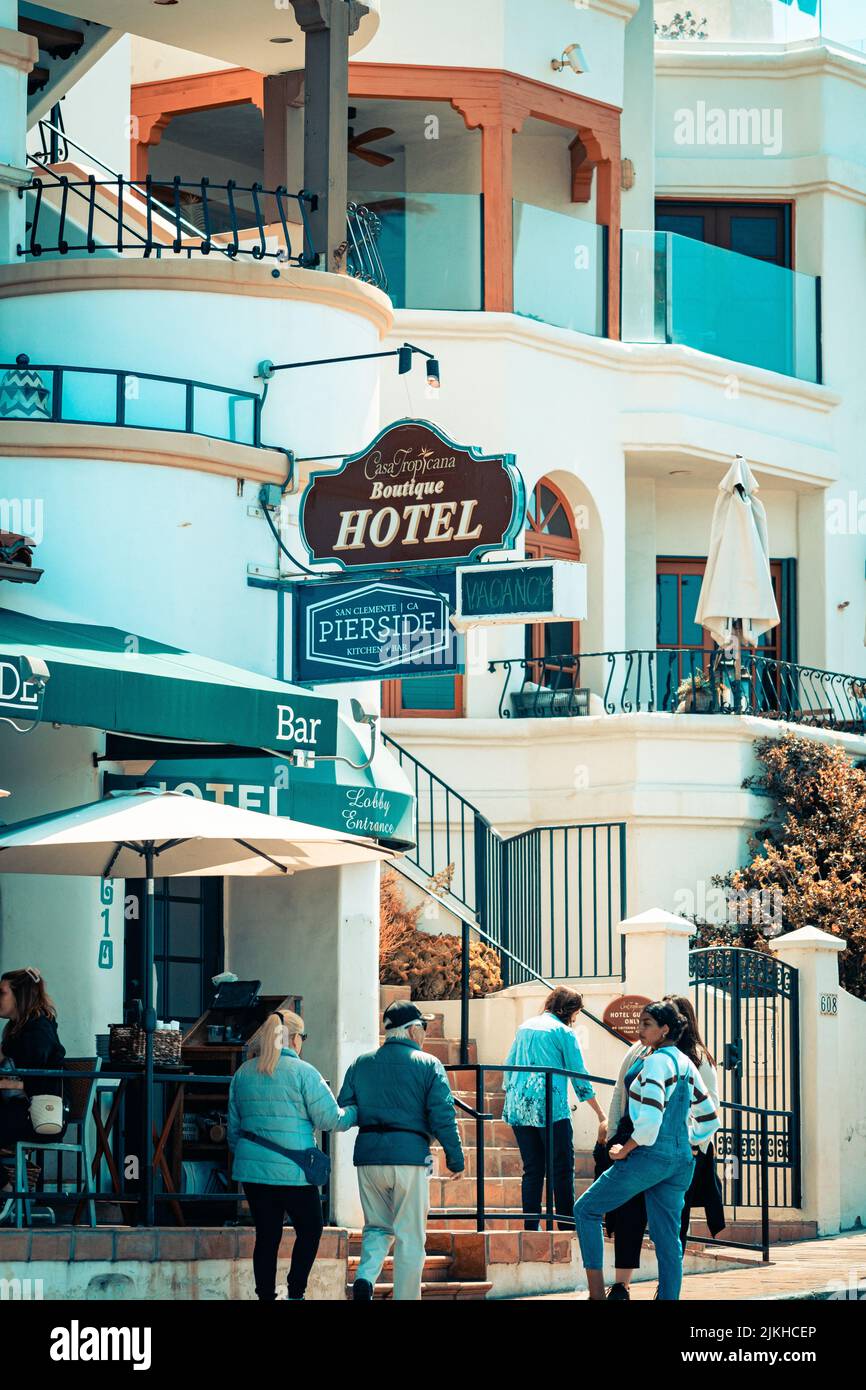 Eine vertikale Aufnahme des weißen Hotels 'Casa Tropicana' mit niedlichen Balkonen und Touristen draußen in San Clemente, CA Stockfoto