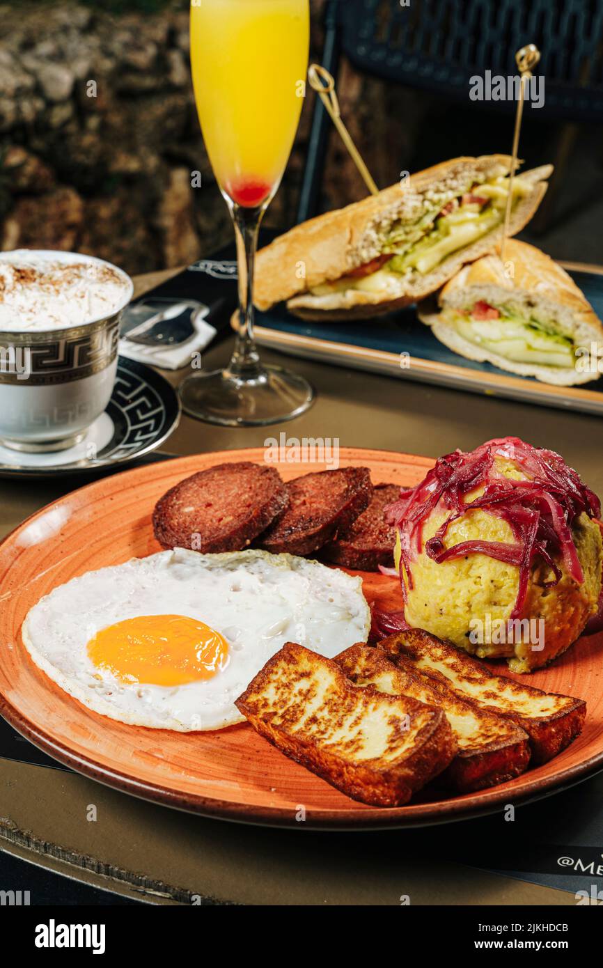 Eine vertikale Nahaufnahme eines dominikanischen Frühstücks mit Ei und gebratenem Fleisch und Sandwiches auf einer Terrasse Stockfoto