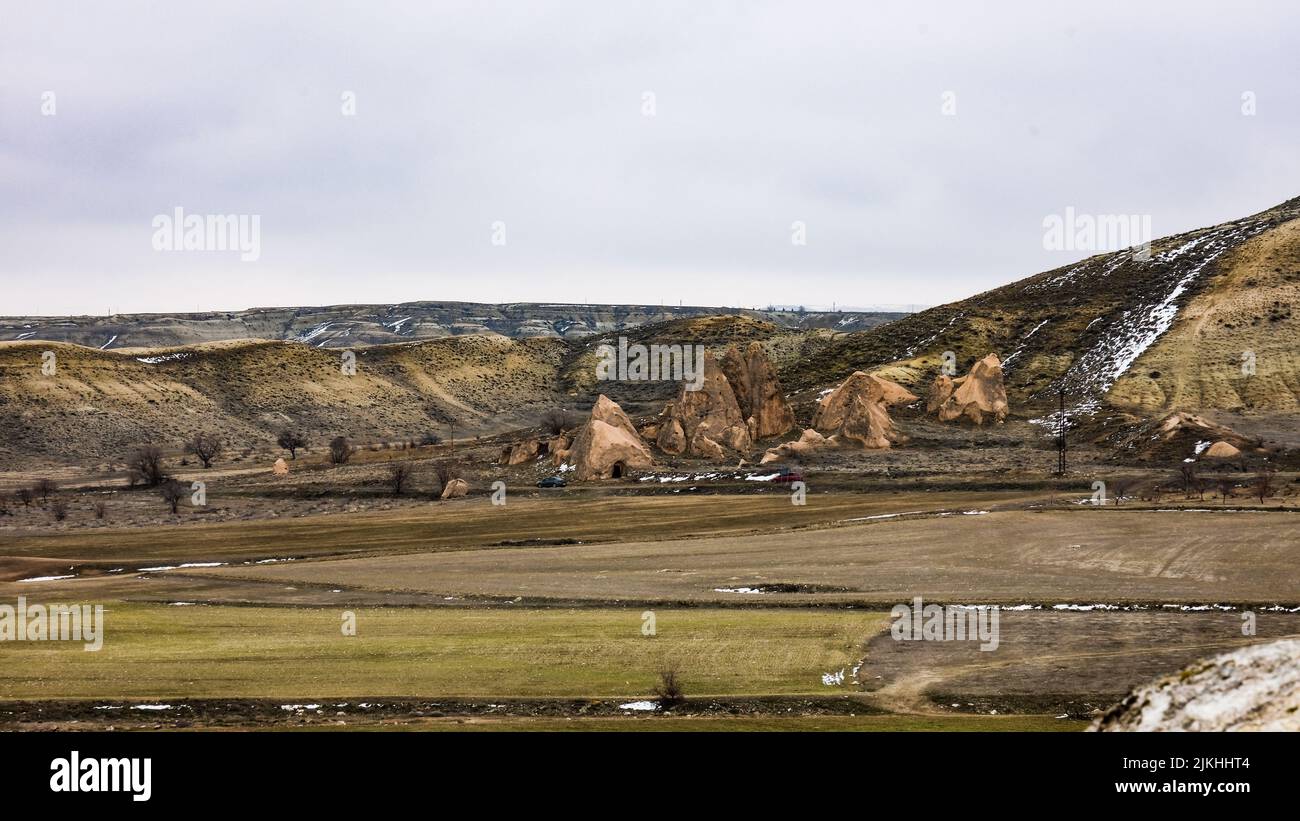 Blick auf graue und beige geologische Formationen und Gesteine in der Nähe eines grünen Feldes in Kappadokien, Türkei Stockfoto