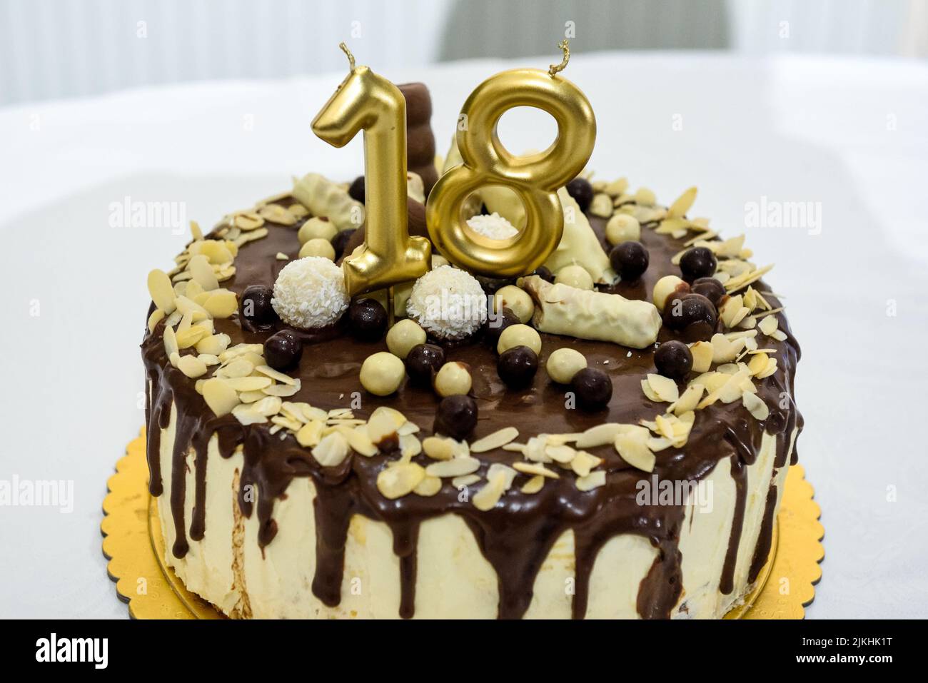 Eine festliche Torte mit goldenen Kerzen für einen achtzehnten Geburtstag oder eine Jubiläumsfeier auf einem weißen Tisch Stockfoto