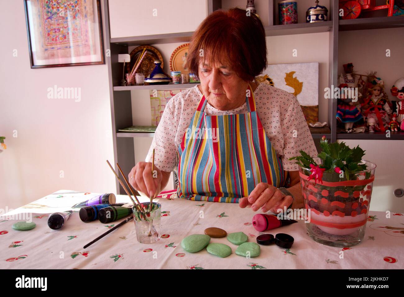 Eine reife kaukasische Frau, die zu Hause in Barcelona, Spanien, Steine mit Acrylfarben malt Stockfoto