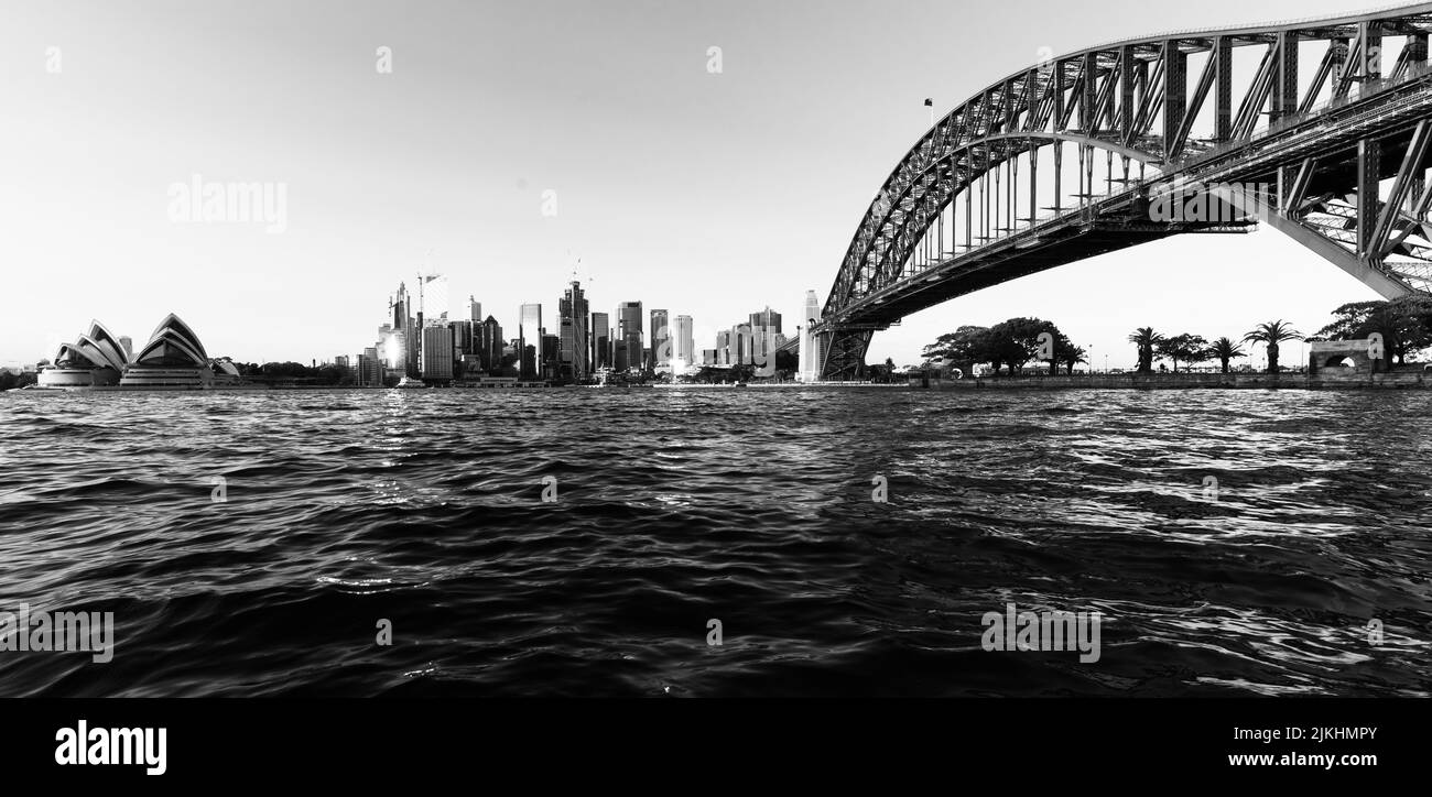 Eine Low-Angle-Aufnahme des Sydney Harbour mit dem Opernhaus und der Harbour Bridge in Schwarz-Weiß Stockfoto