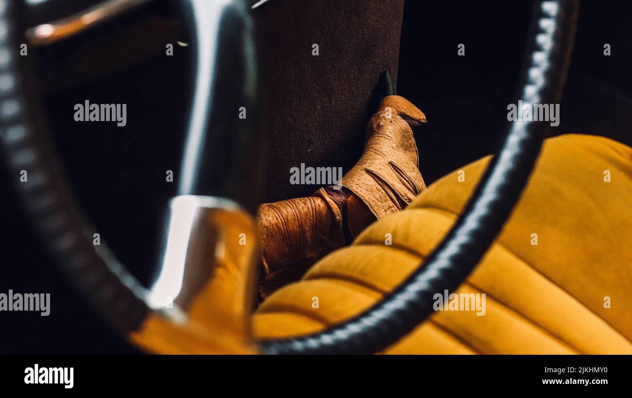 Nahaufnahme eines Oldtimer-Innenraums mit braunen, sportlichen Lederhandschuhen bei Tageslicht Stockfoto