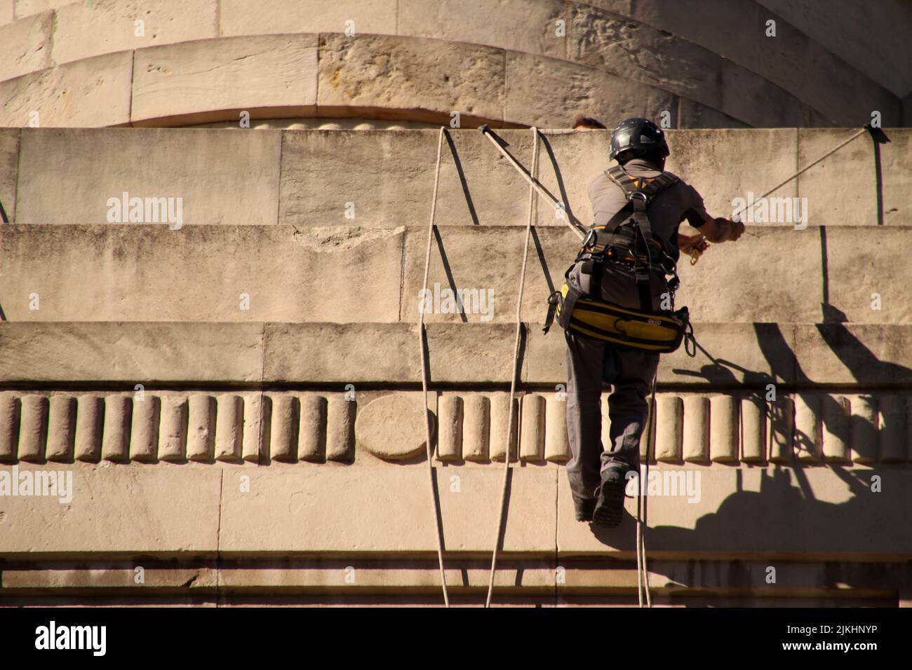 Ein Bauarbeiter in einem Helm mit Sonderausrüstung auf einem Steingebäude Stockfoto
