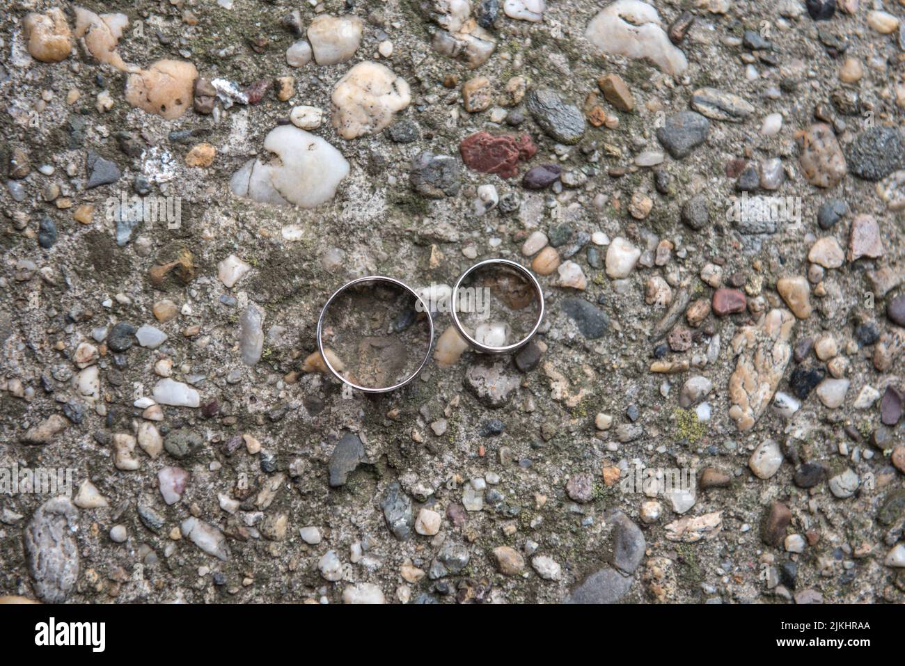 Eine Nahaufnahme von zwei Eheringen auf dem strukturierten Boden Stockfoto