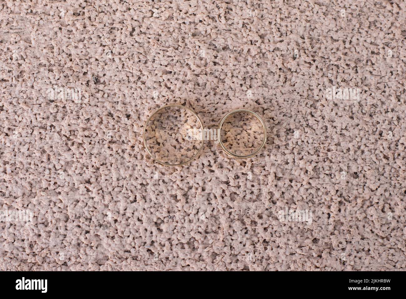 Eine Nahaufnahme von zwei Eheringen auf dem strukturierten Boden Stockfoto