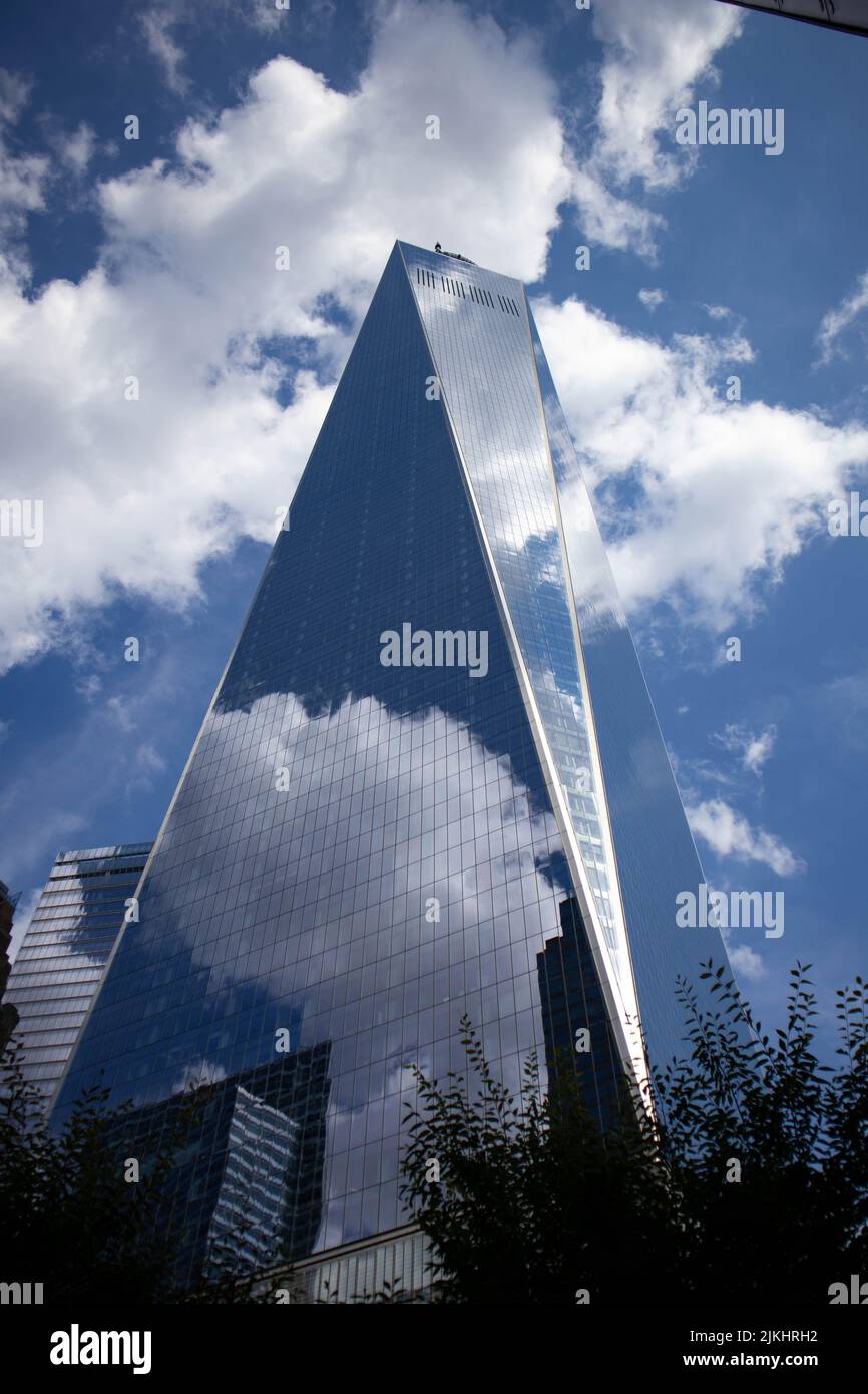 Eine vertikale Aufnahme eines Wolkenkratzers im Welthandelszentrum, der den bewölkten Himmel in New York City reflektiert. Stockfoto