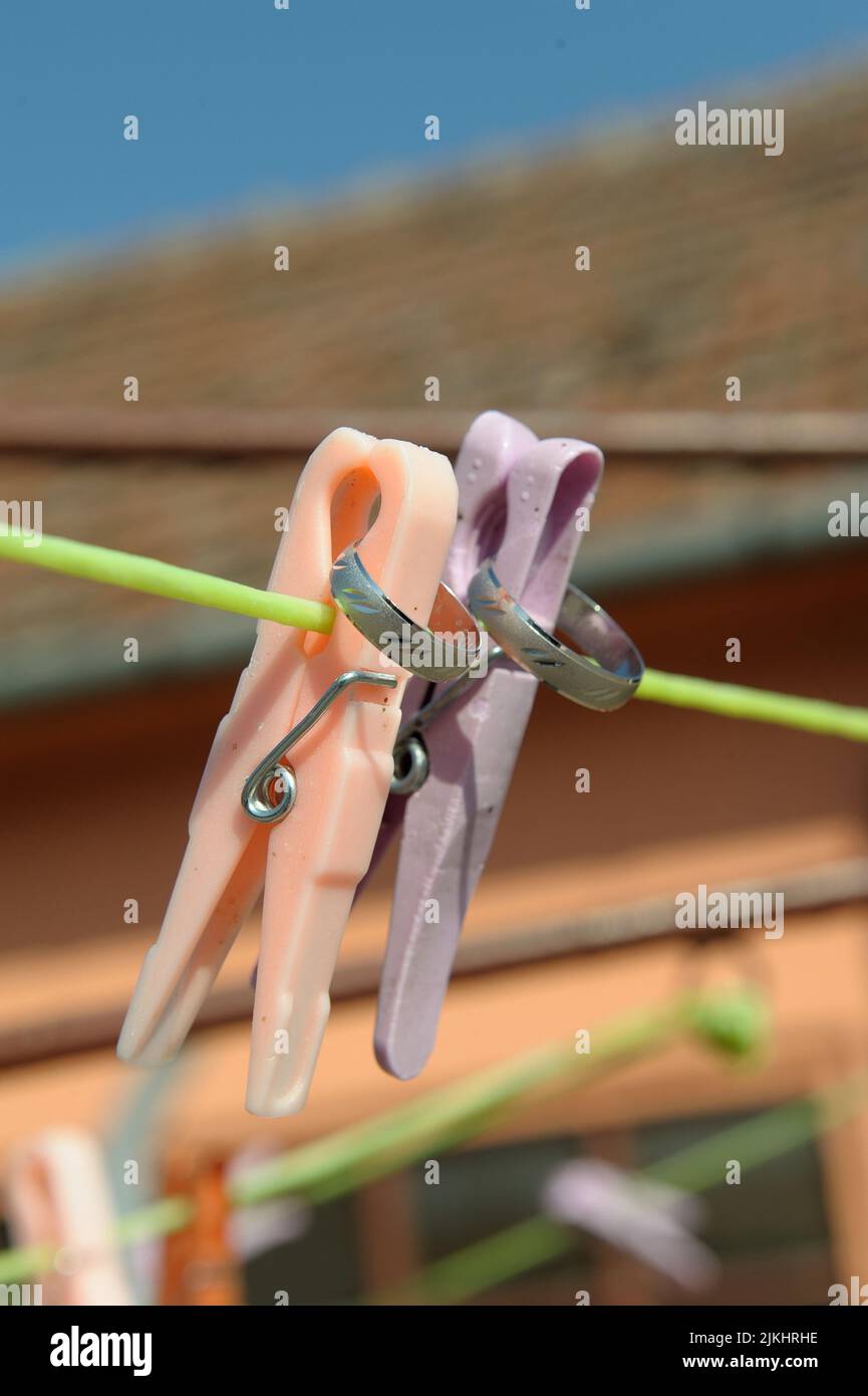 Eine vertikale Nahaufnahme von zwei Eheringen auf den Wäscheklammern Stockfoto