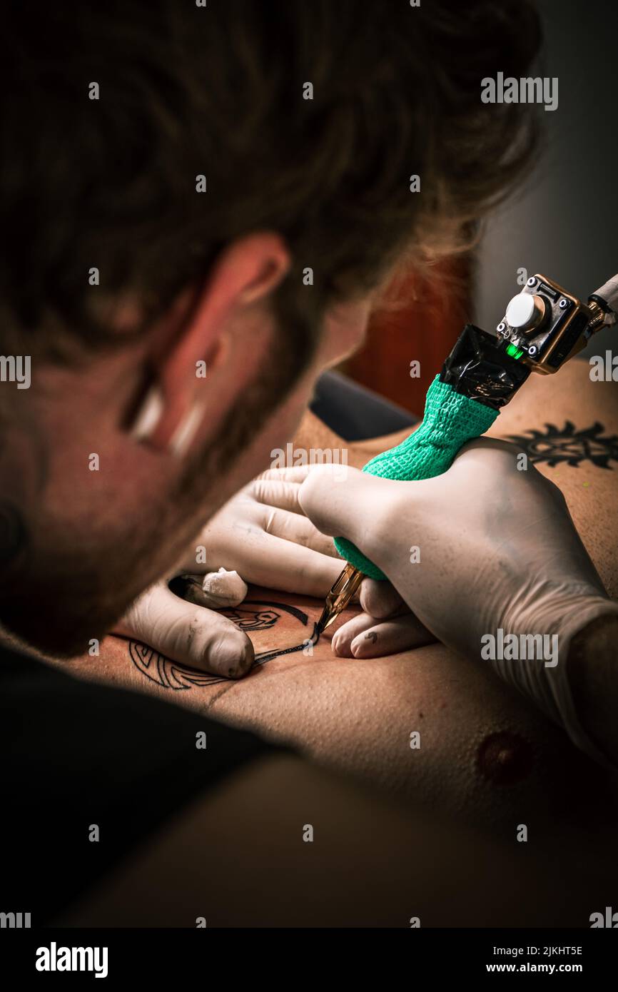 Eine vertikale selektive Fokusaufnahme eines Tätowierers während der Arbeit Stockfoto