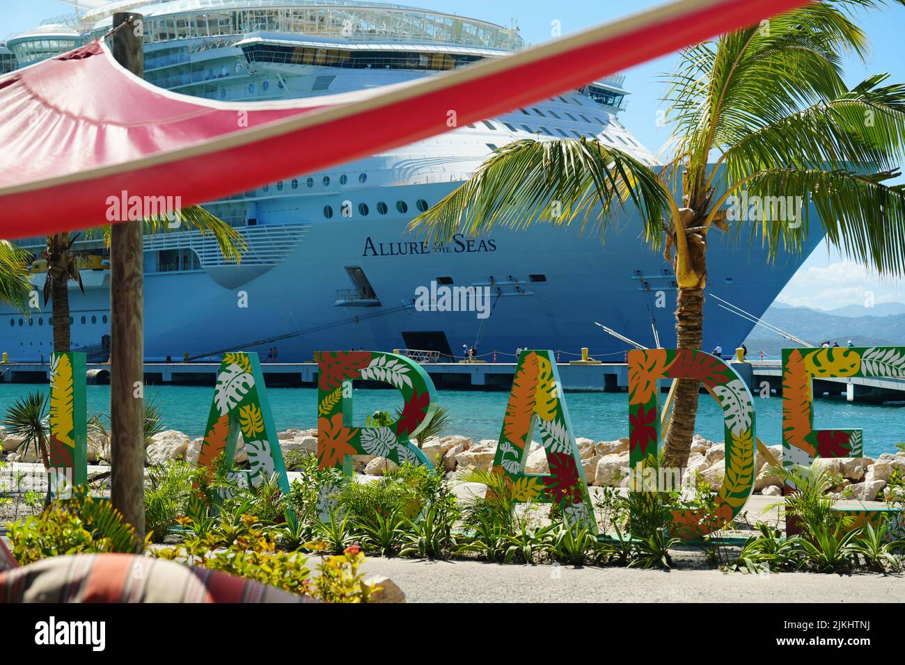 Eine selektive Fokusaufnahme des Strandschildes Labadee mit dem Schiff Allure of the Seas im Hintergrund Stockfoto