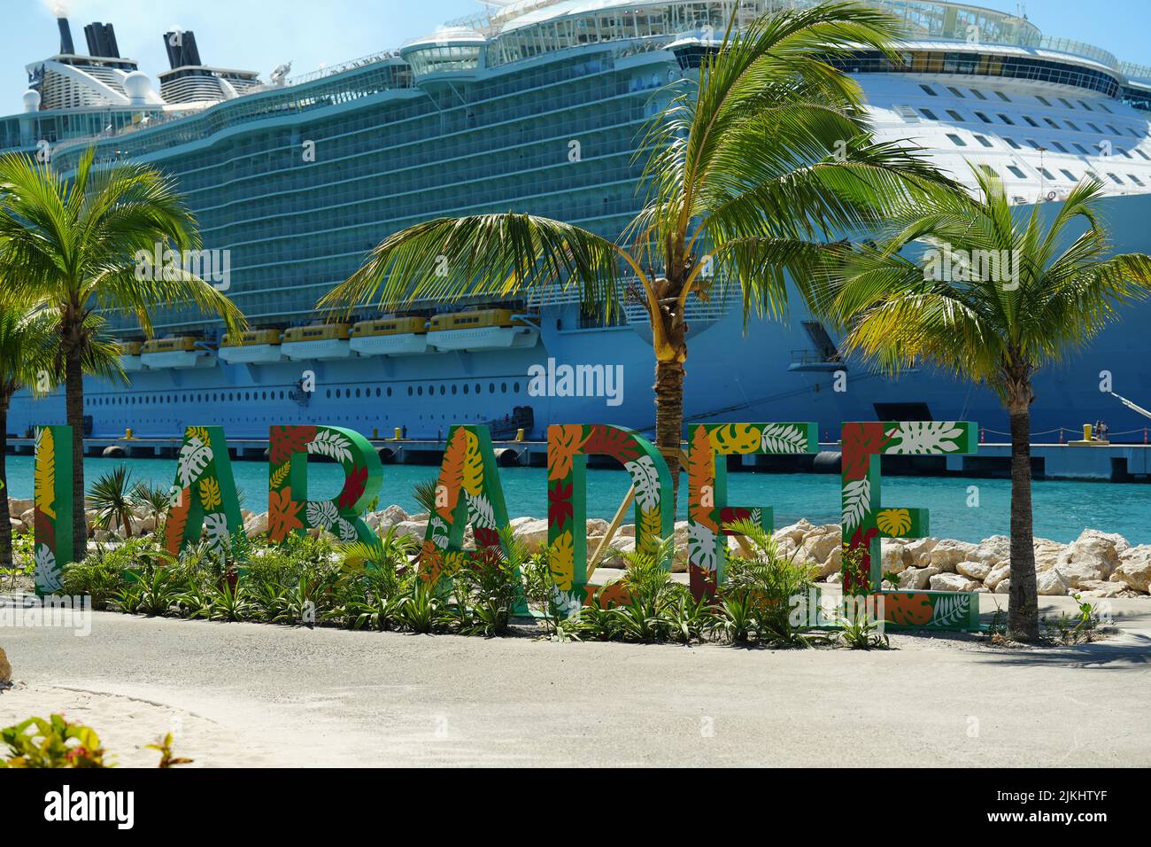 Eine selektive Fokusaufnahme des Strandschildes Labadee mit dem Schiff Allure of the Seas im Hintergrund Stockfoto