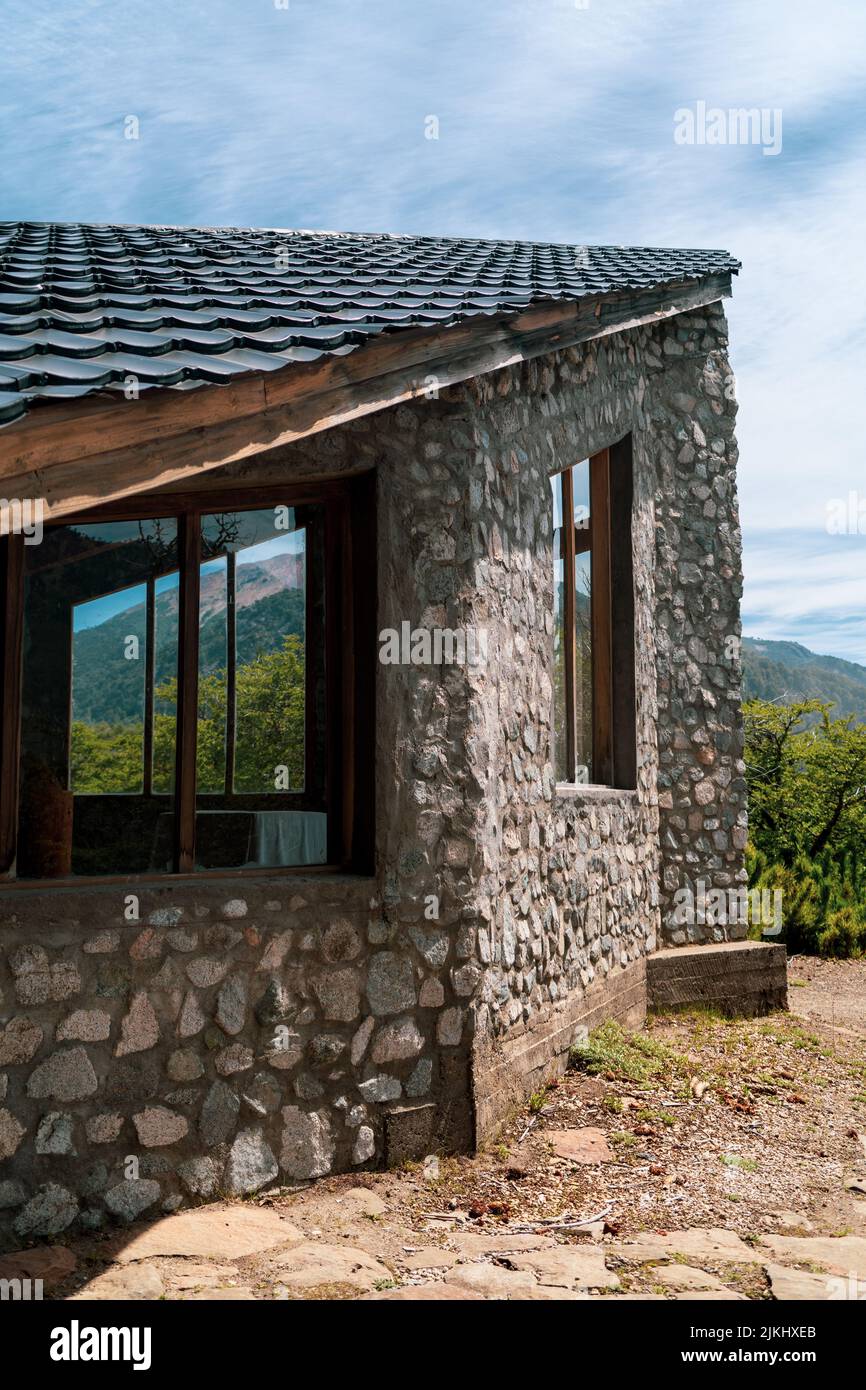 Eine vertikale Aufnahme eines Steinhauses mit Kunststofffenstern, umgeben von einer wunderschönen Landschaft Stockfoto