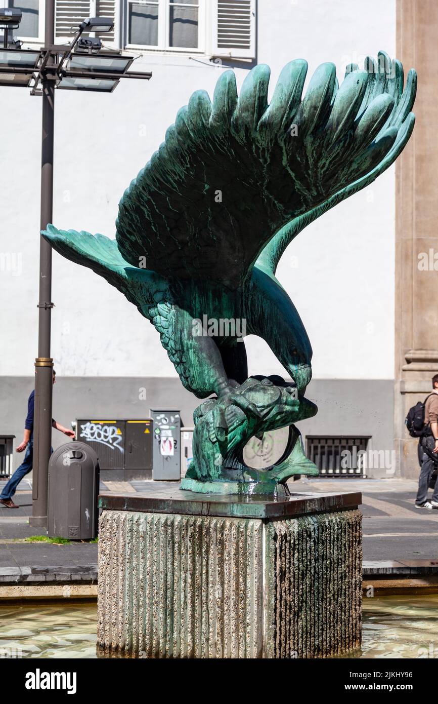 Eine vertikale Aufnahme einer Bronzestatue eines Adlers, der in der Innenstadt von Antwerpen, Belgien, einen Fisch frisst. Stockfoto
